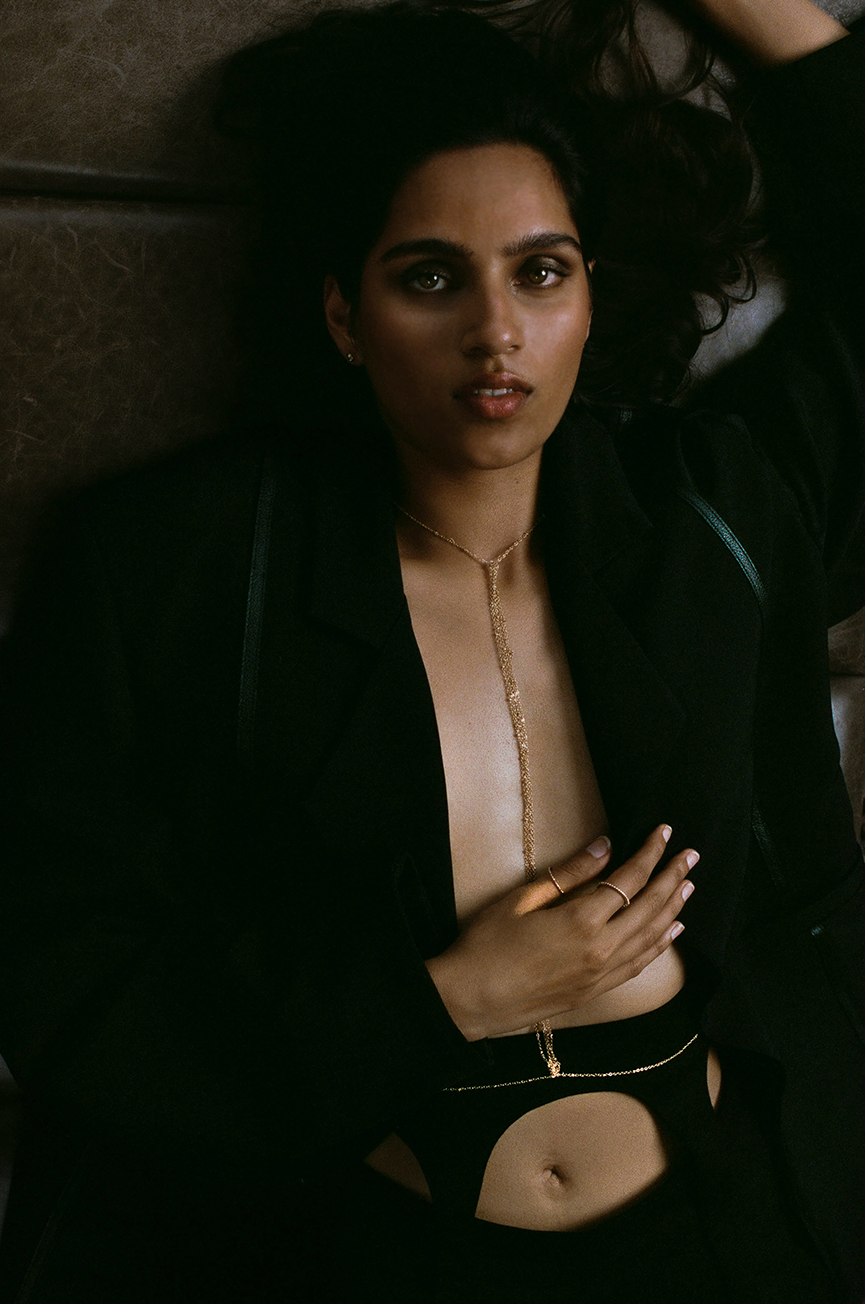 Model laying on the ground with an open black blazer looking at the camera with smokey eye makeup